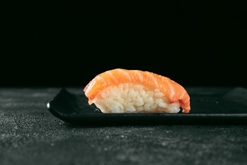 Nigiri sushi with salmon on a black board. Japanese kitchen. Food delivery. Black background