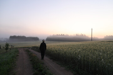 silhouette of a man walking in a scenic countryside landscape at sunrise