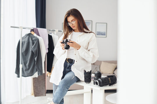 Female photographer in casual clothes is working indoors at daytime