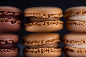 chocolate, coffee, vanilla, lemon and strawberry macaroons on black background