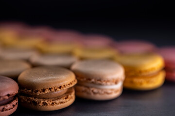 chocolate, coffee, vanilla, lemon and strawberry macaroons on black background