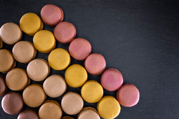 chocolate, coffee, vanilla, lemon and strawberry macaroons on black background