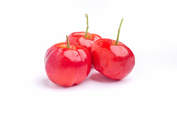 Three red acerola cherries fruit isolated on a white background. High vitamin C and antioxidant fruits. Close-up. Concept of healthy fruits