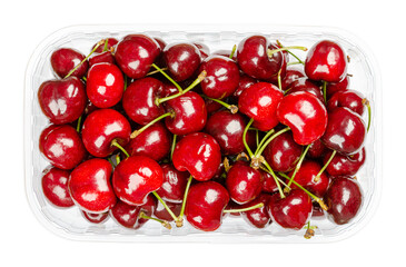Fresh cherries in a plastic container. Ready to eat, red and ripe fruits of the true cherry species Prunus avium, a stone fruit cultivar. Close-up, from above, isolated, over white, macro food photo.