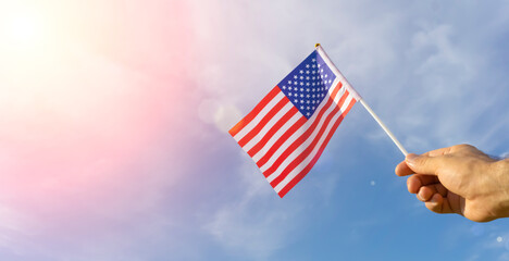 USA flag in hand. Festive USA flag in hand against blue sky and summer natural landscape. American holidays concept.