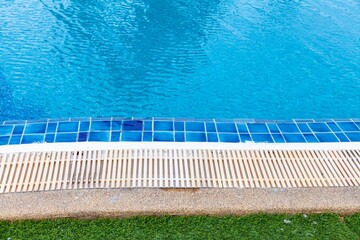 Fototapeta na wymiar Wide swimming pool and green artificial turf inside the villa