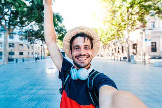 Happy tourist man taking selfie with smart phone device on city street - Smiling guy looking at camera outside - Youth, vacations and technology concept