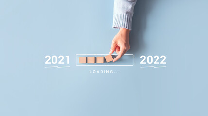 Loading new year 2021 to 2022 with hand putting wood cube in progress bar.