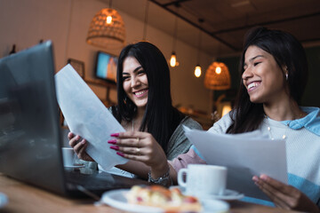 Young women studying with their laptops at a bar.