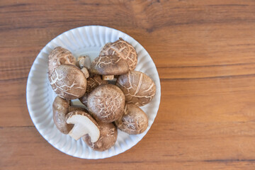 Group Shiitake mushrooms on dish on wooden background. Copy space for your text. Top view