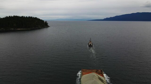 Aerial shot of tug boat towing sand in British Columbia.