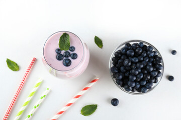 Studio shot of one blueberry milkshake glass. Single protein shake drink with berries isolated on white background. Clean eating concept. Copy space for text, close up, top view