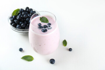 Studio shot of one blueberry milkshake glass. Single protein shake drink with berries on kitchen counter. White brick wall background. Clean eating concept. Copy space, close up, top view