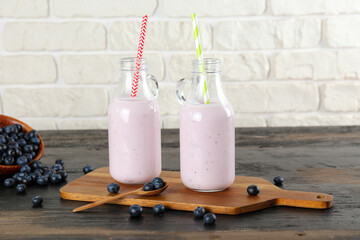 Two blueberry milkshake bottles on black wooden table. Couple of protein shake drinks with berries...