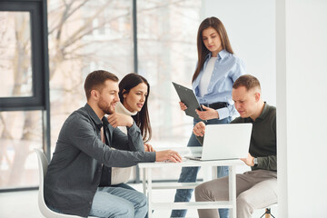 Four people works in the office by sitting by the table indoors