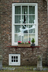 Fototapeta na wymiar white window with flowers on the brick wall