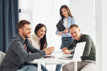 Four people works in the office by sitting by the table indoors