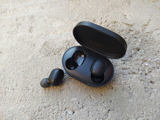Portable device - headphones. A man's hand uses wireless headphones, with a charging case.