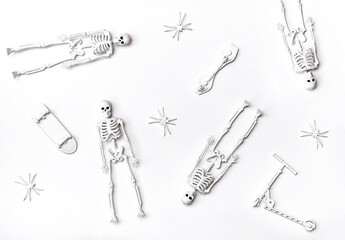 Flat lay of skeletons, skateboards, scooter and spiders. White toys on the white background....