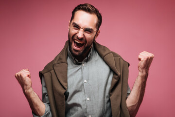 Man in shirt and sweater rejoices on pink background