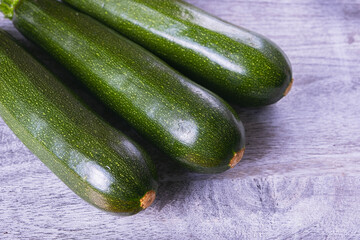 three young zucchini lie on a wooden board