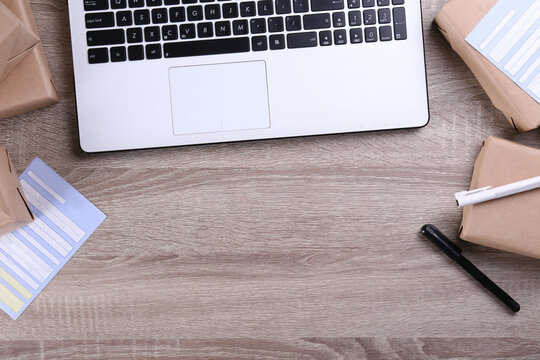 Stacked packages of different sizes wrapped in craft paper with shipping labels. Laptop and parcels on table. Shipping software for ecommerce fulfillment concept. Close up, copy space, background.
