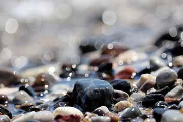 Wet pebble stones on blurred background of sea waves. Summer vacation concept