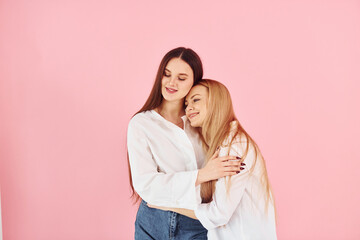 Embracing each other. Young mother with her daughter standing in the studio