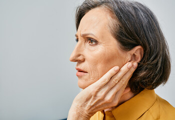Hearing loss. Mature woman with hearing problems touching ear with hand. Side view, earache