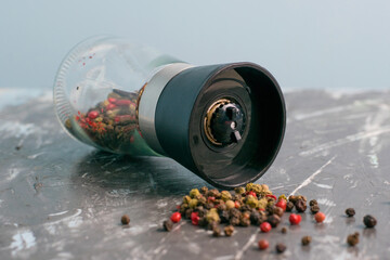 Pepper mill with mixture of peppercorns close up on dark concrete background © queen1987