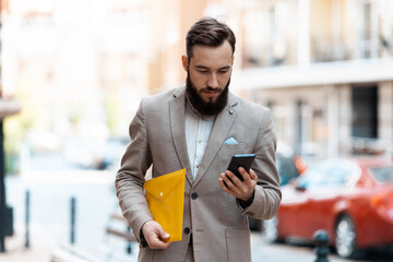 Serious businessman reads a message on a smartphone. Be late for work. Hurrying to a business...