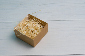 Craft gift box with light wood filler on wooden background with copy space