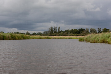 Un rayon de soleil sur le marais de Brière alors que le ciel menace avec de nombreux nuages noirs.