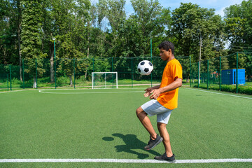 Young Brazilian football player kicking and stuffing soccer ball outdoors