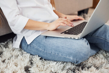 Naklejka premium Working from home. Young woman in white shirt and jeans indoors