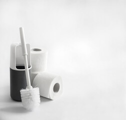 White and gray plastic toilet brush and toilet paper on white background
