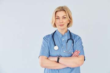 Middle-aged professional female doctor in uniform and with stethoscope