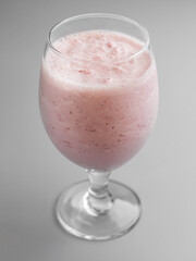 Delicious cold raspberry milkshake in glass on gray background