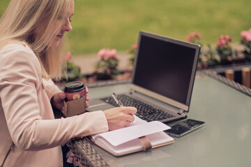 Beautiful woman working with laptop, on the street of old city on summer day, waist up