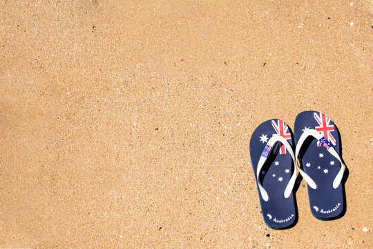 Australia Day and travel destination background:. Aussie thongs featuring Australian flag on the sand