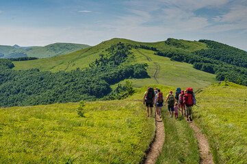 A group of tourists with large backpacks is walking along the beautiful water-producing ridge in the Carpathians. Ukraine