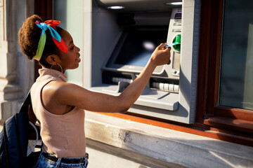 Beautiful african women using ATM machine. Attractive young woman withdrawing money from credit...