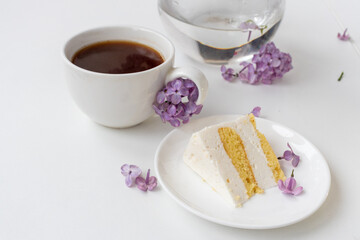 Cup of coffee and cake horns fromstill life with a bouquet of lilacs on a white table, a cup of coffee, a plate with a piece of cake. international Women's Day, March 8