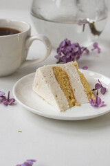 Cup of coffee and cake horns fromstill life with a bouquet of lilacs on a white table, a cup of coffee, a plate with a piece of cake. international Women's Day, March 8