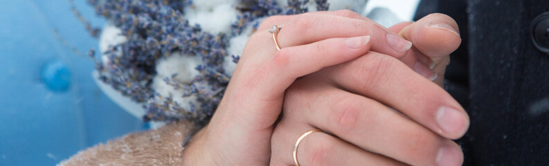 Hands of the newlyweds close-up and wedding rings. Girl holds a bouquet with lavender. Tender sensual couple.