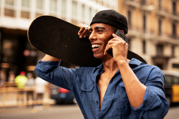 Portrait of happy african-american man with skateboard. Young handsome man with skateboard outdoors..