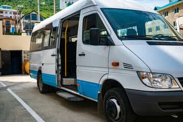 Plakat Tourist minibus is waiting with the door open in the parking lot. White minibus is parked in sunny weather.