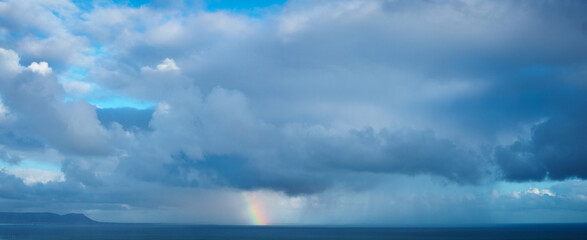 Obraz premium Rain squall, rainbow and storm at sea. Hermanus, Whale Coast, Overberg, Western Cape. South Africa