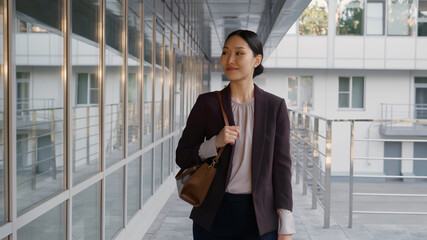 Young asian businesswoman commuting to work outside modern office building