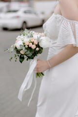 Obraz na płótnie Canvas Bride in a white wedding dress Bouquet of roses in female hands